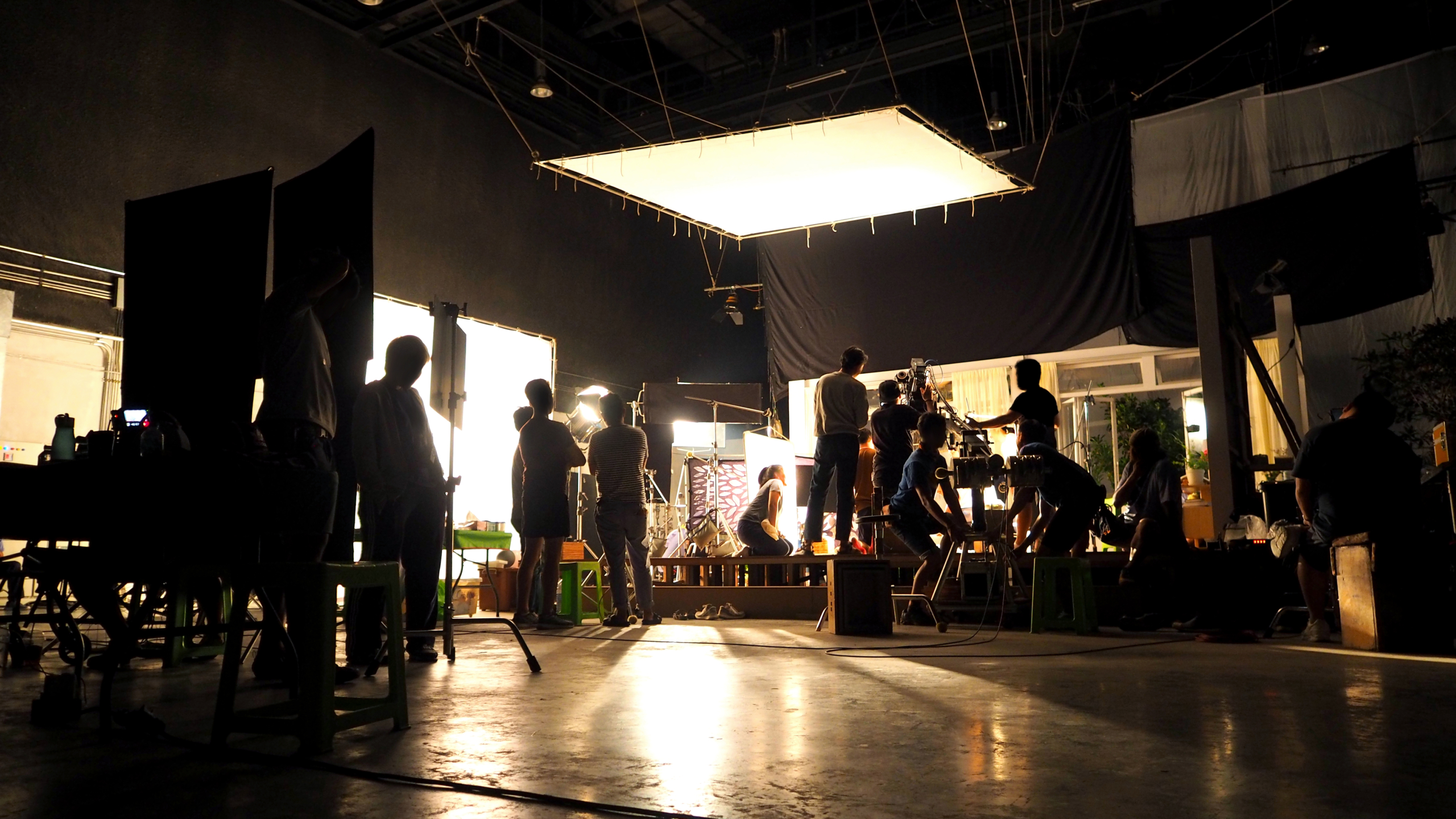Behind the scenes or the making of film video production and movie crew team working in silhouette of camera and equipment set in studio.